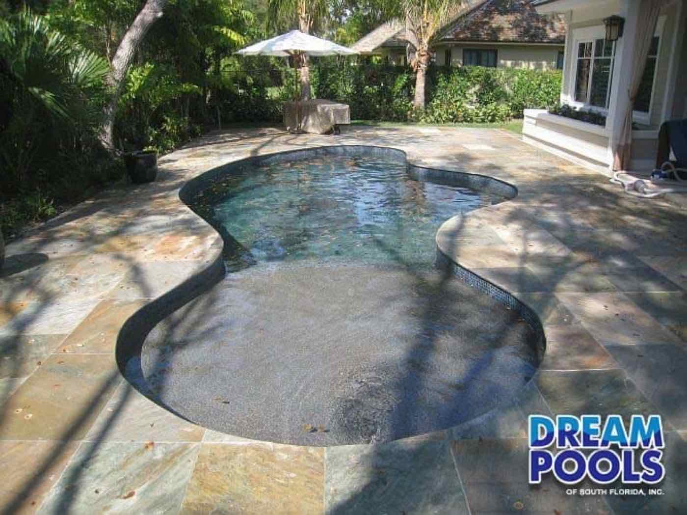Freeform pool with tiled deck and tropical landscaping