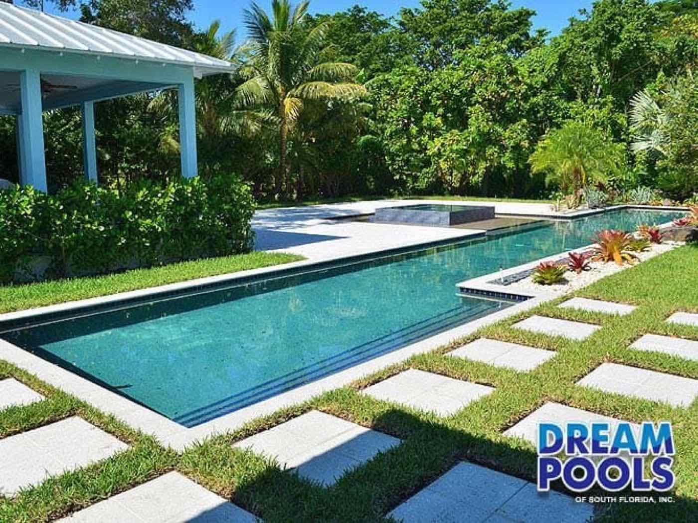 Rectangular pool with stone pavers, grass surround, and covered seating area